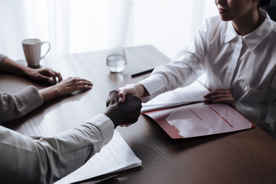 Professional handshake between diverse individuals over a business contract indoors.